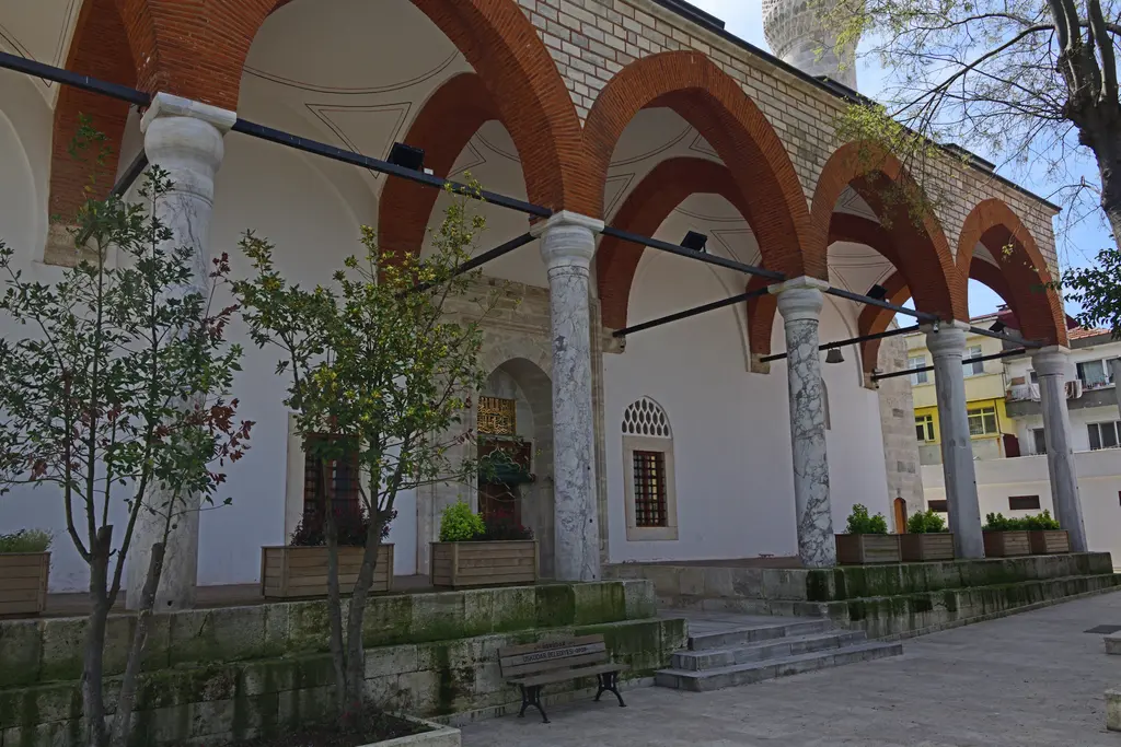 Rum Mehmed Paşa Camii'nin son cemaat yeri; kırmızı kemerler, beyaz sıvalı duvar, mermer sütunlar ve önünde fidanlar.