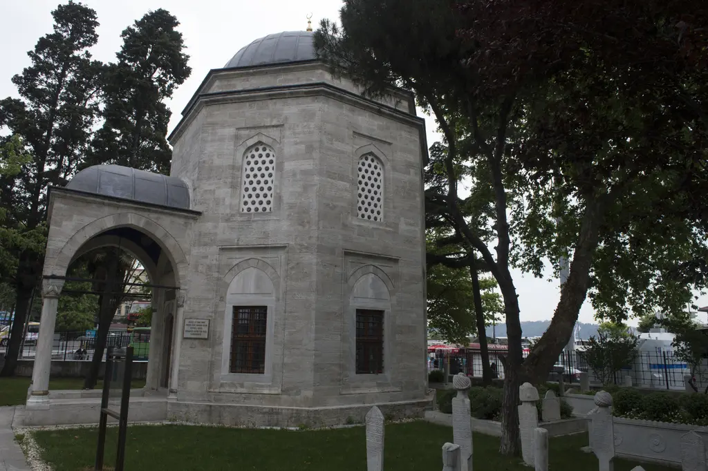 Beşiktaş'ta Barbaros Hayreddin Paşa Türbesi; kesme taş sekizgen gövde, kurşun kubbe, önde revak ve çevresinde ağaçlar.