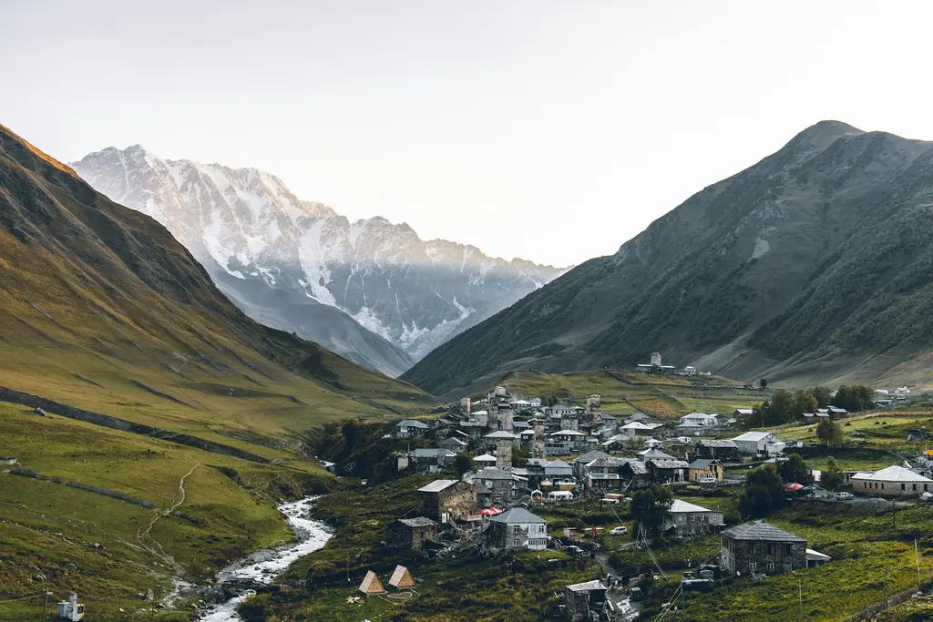 Svaneti'de Ushguli köyünün ortaçağ taş savunma kuleleri; arkada karlı Şhara Dağı ve yeşil yamaçlar.