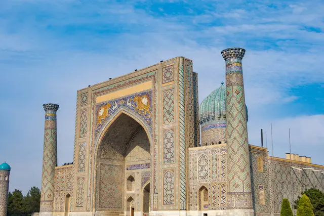 Semerkant'ta Registan Meydanı; üç yanı çini kaplı anıtsal medreselerle çevrili taş meydan, mavi kubbeler ve yüksek portaller.