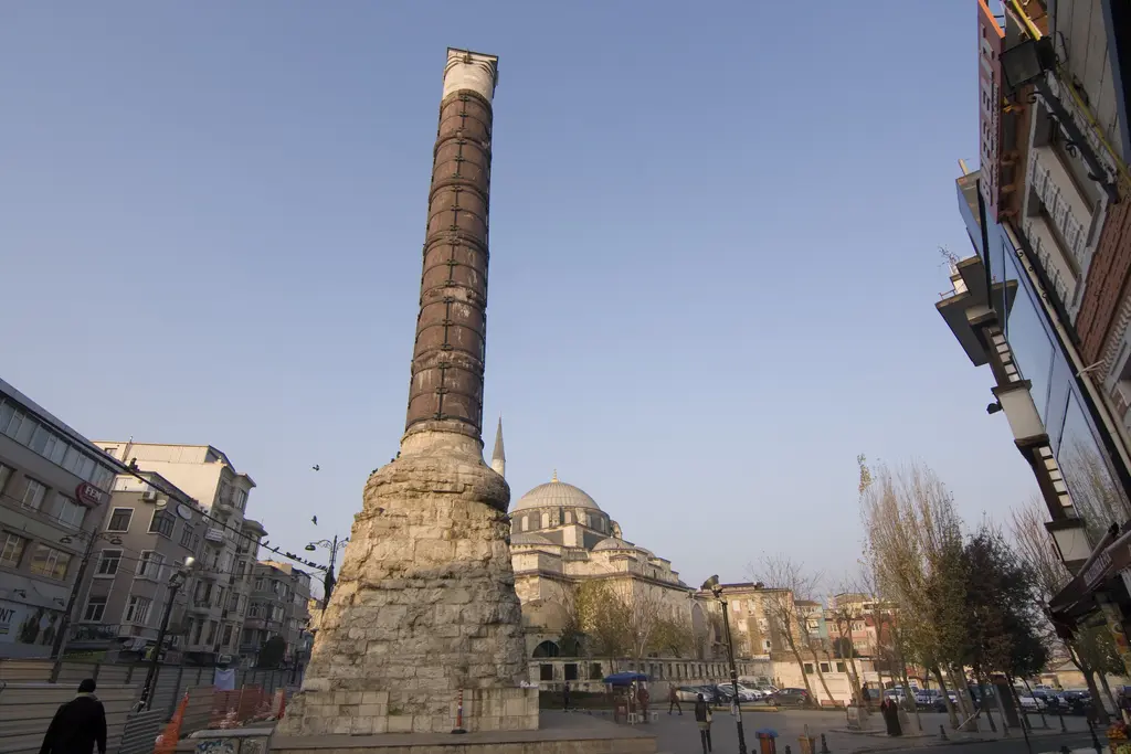 Çemberlitaş'ta meydanın genel görünümü; ortada sütun, çevresinde taş döşeli alan, arkada kubbesiyle bir cami ve çıplak ağaçlar.