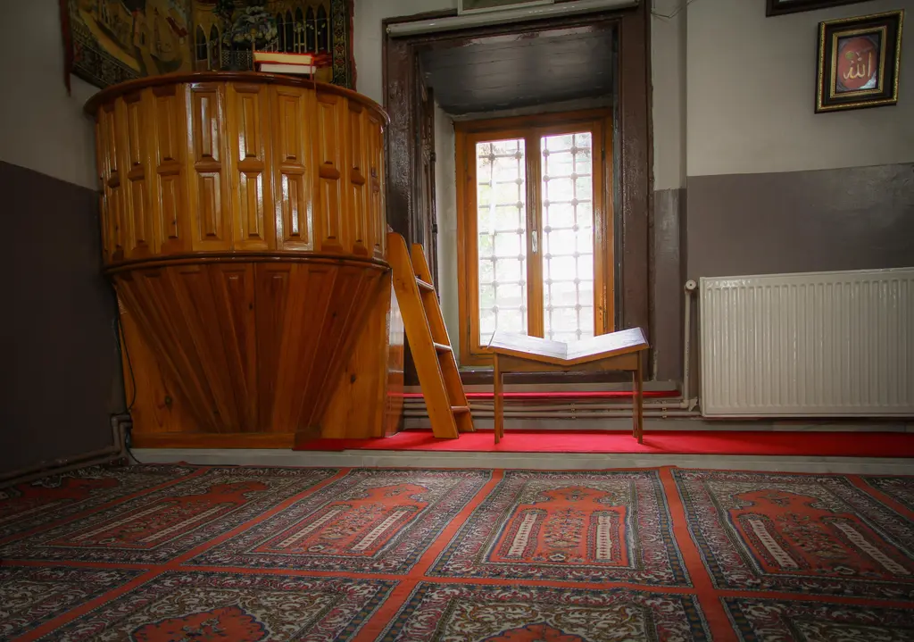Rum Mehmed Paşa Camii'nde vaaz kürsüsü; ahşap kürsü, merdiveni, rahle üstünde açık kitap ve arkada pencere.