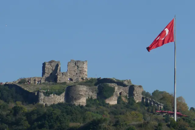 Beykoz'da Yoros Kalesi; yeşil tepenin üstünde iki yüksek taş kule, yuvarlak burçlar, surlar ve dalgalanan bayrak.