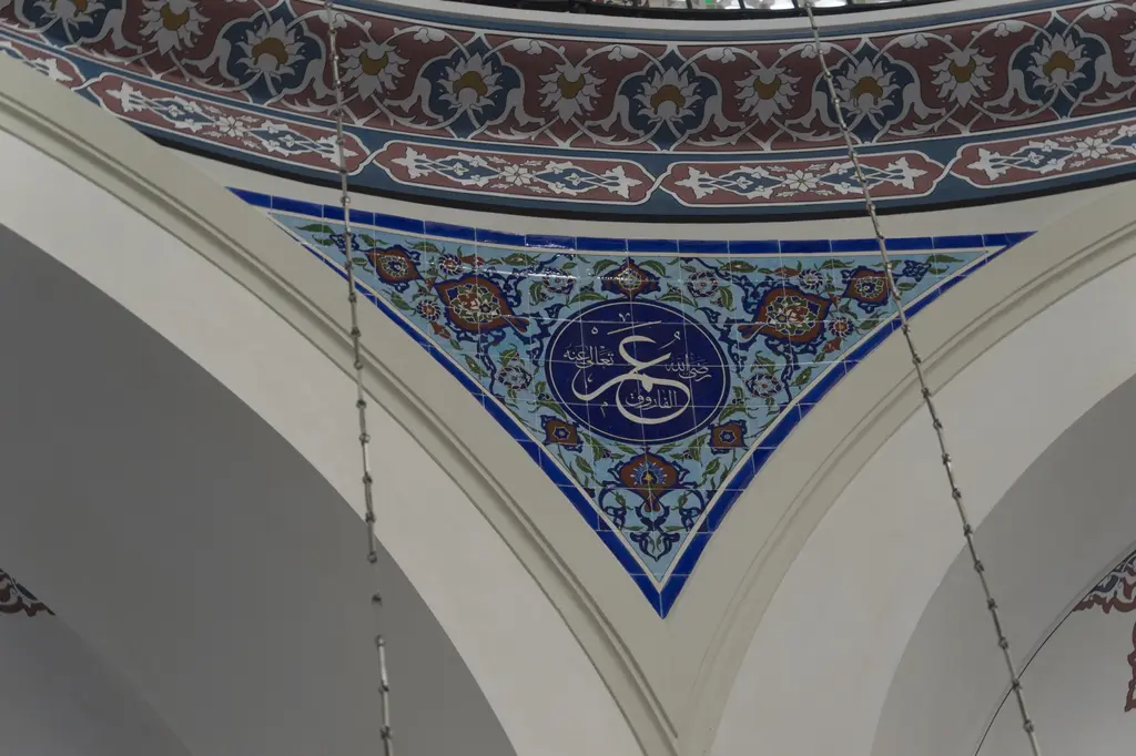 Azapkapı Sokullu Mehmed Paşa Camii'nde kemer köşesi; lacivert çerçeveli üçgen yüzey, ortada yuvarlak yazı madalyonu ve kırmızı bordürler.