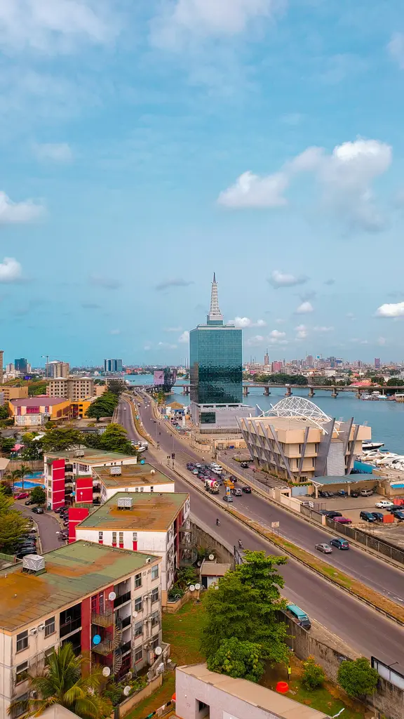 Nijerya'nın en büyük kenti Lagos'un lagün kıyısındaki manzarası; camdan Civic Centre Towers gökdeleni, sahil yolu trafiği ve açık mavi gökyüzü.