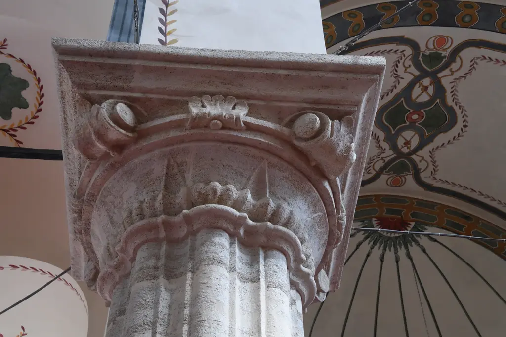 Zeyrek Camii'nde sütun başlığı; taşa oyulmuş kıvrık yapraklar ile boynuz biçimli çıkıntılar, üstünde profilli blok, arkada kalem işi bezeli kemer.