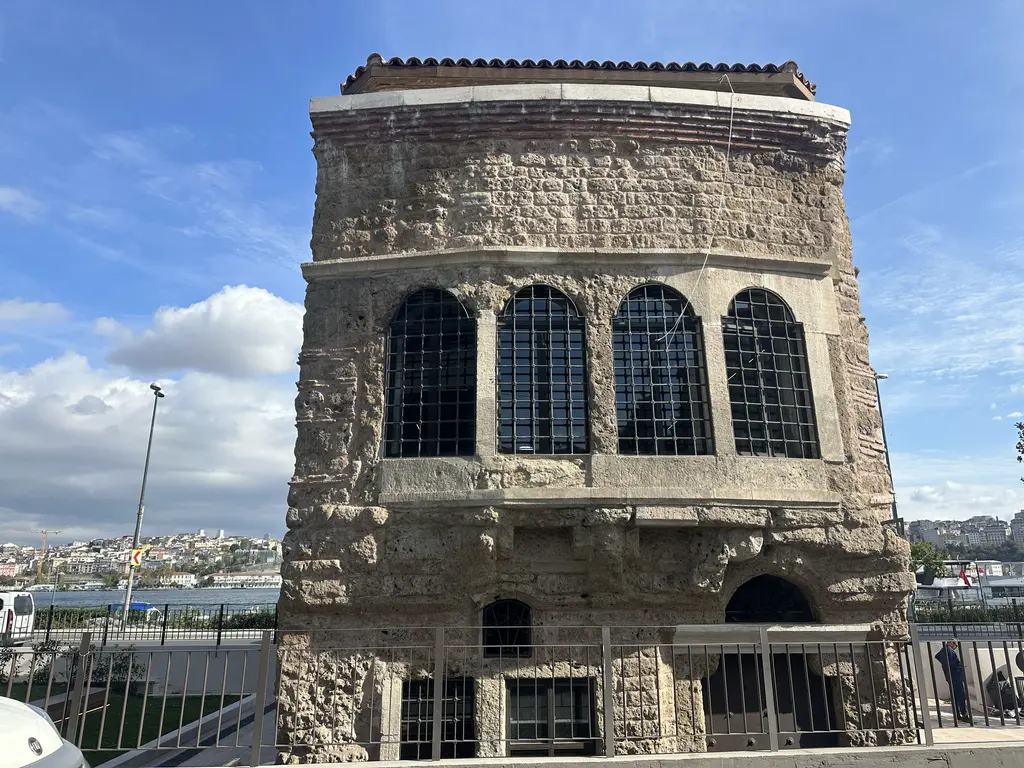 Ceneviz Evi diye anılan taş yapı; kemerli büyük pencereler, moloz taş duvarlar, demir parmaklıklar ve arkada Haliç.