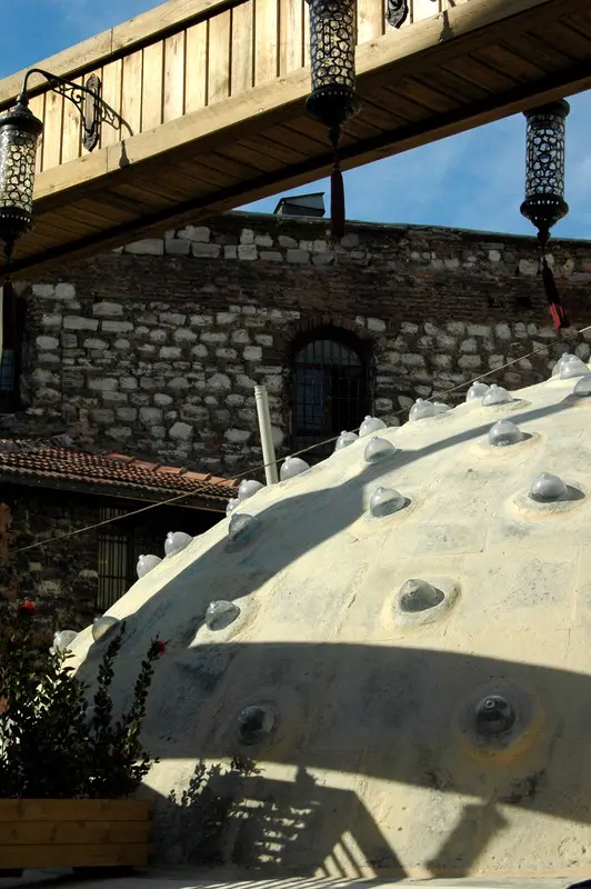 Çemberlitaş Hamamı'nın kubbesi yakından; kurşun kaplamanın üstüne oturtulmuş sıra sıra cam aydınlık göbeği ve arkada kesme taş duvar.
