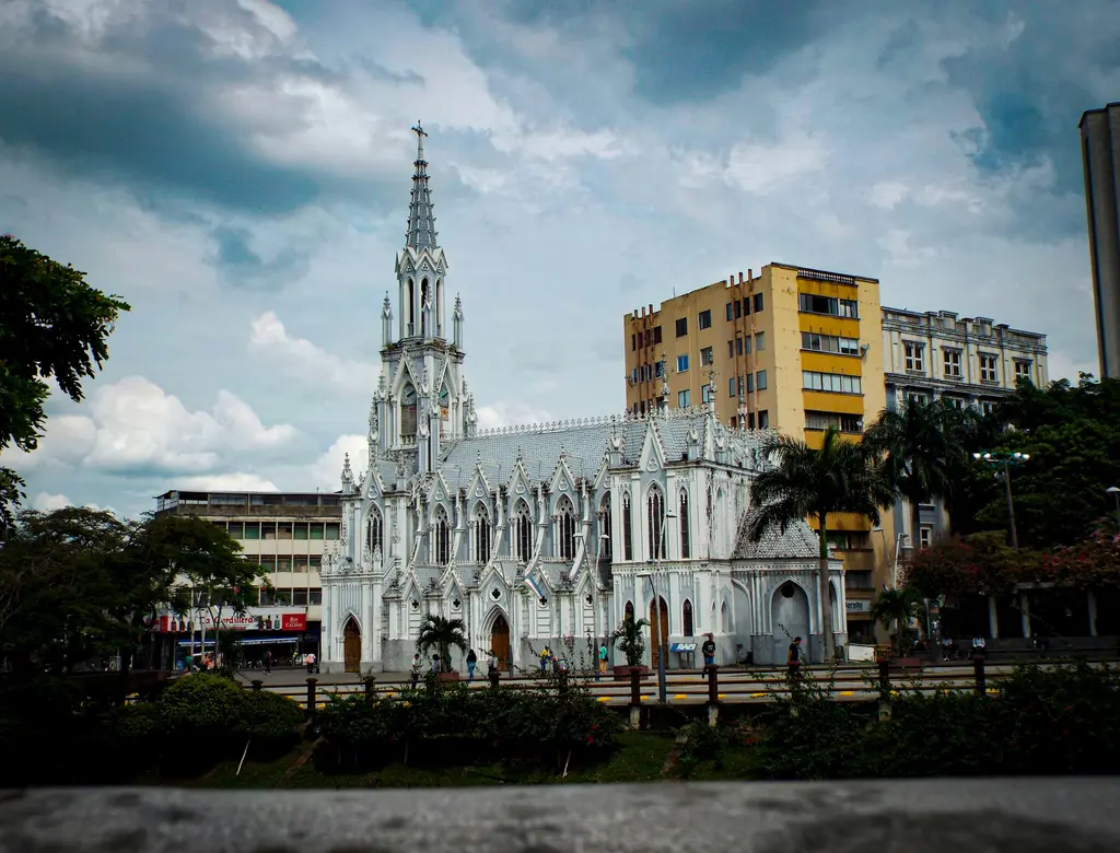 Cali'de La Ermita Kilisesi; beyaz ve açık mavi neogotik cephe, ince sivri kulesi ve arkasındaki modern binalar.