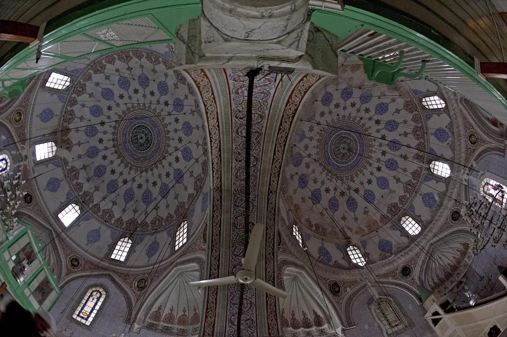 Haseki Sultan Camii'nin iki kubbesine alttan bakış; mavi ve kırmızı kalem işi desenler, pencereler, ortada iki kubbeyi ayıran kemer.