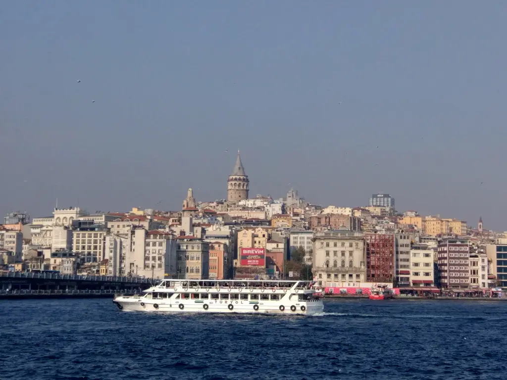 Haliç'ten Karaköy ve Galata yamacı; kıyıda büyük bir yolcu teknesi, tepede Galata Kulesi ve iç içe binalar.