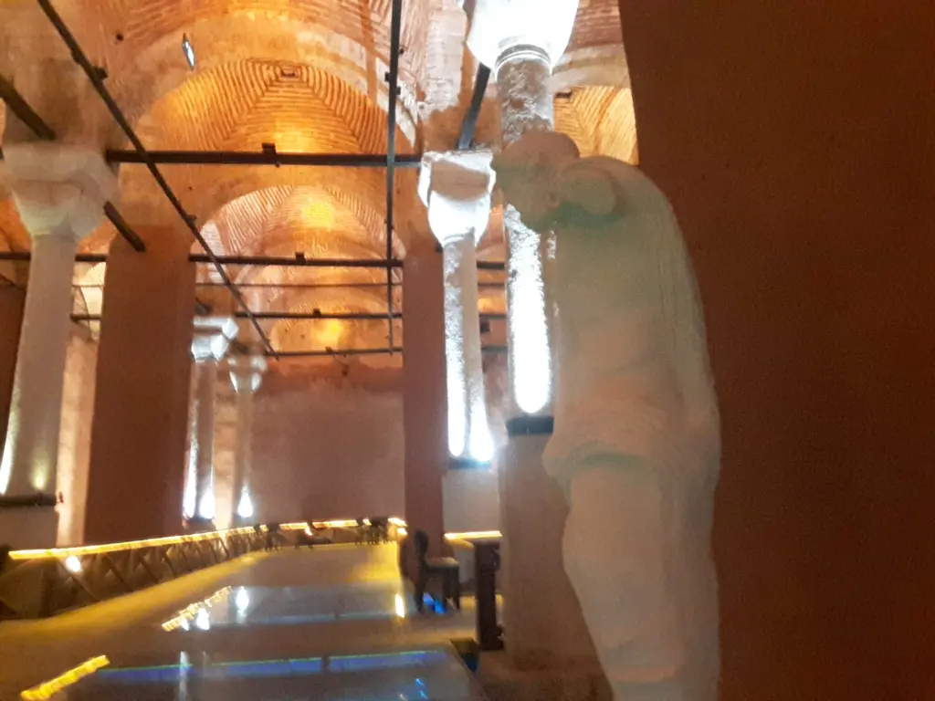 Zeyrek Sarnıcı'nda beyaz bir heykel; arkada sütun sıraları, turuncu tonozlar, ışıklı yürüme yolu ve parlak zemin.
