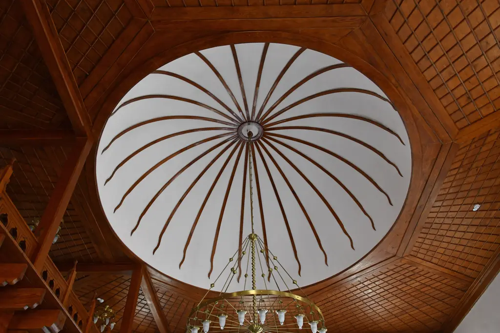Şah Sultan Camii'nde tavan; sekizgen ahşap çerçeve, beyaz dilimli kubbe, avize ve köşede renkli camlı pencere.