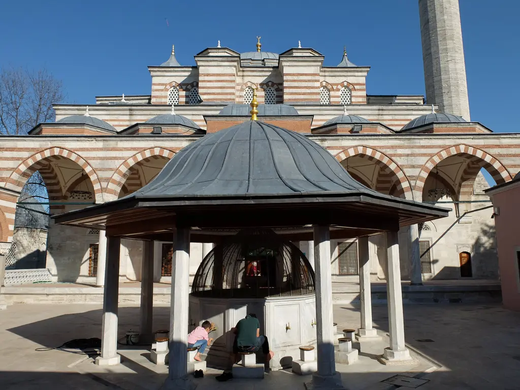 Zal Mahmud Paşa Camii'nin avlusu; kurşun külahlı şadırvan, arkada kemerli son cemaat yeri, kubbeler ve minare.