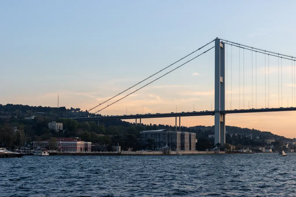 Denizden 15 Temmuz Şehitler Köprüsü; gün batımında asma köprü, altında Boğaz ve kıyıdaki Beylerbeyi yapıları.