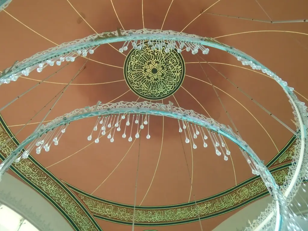 Şakirin Camii'nde kubbe; aşağıdan bakışla kırmızı kubbe içi, ortada hat madalyonu ve önde halkalı avize.