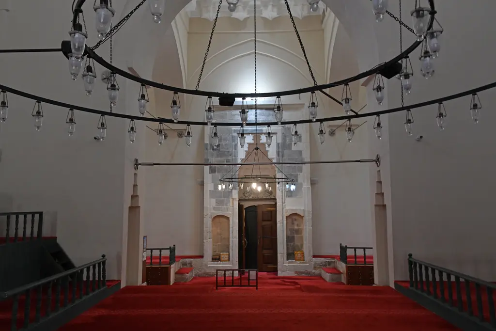 Mahmut Paşa Camii'nin iç giriş mekânı; ortada ahşap kanatlı mermer kapı, halka biçimli avize, kırmızı halı ve iki yanda ahşap korkuluklar.