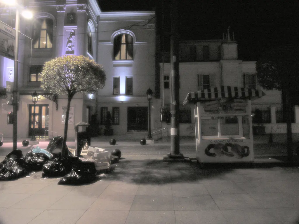 Gece Süreyya Operası; aydınlatılmış cephe, girişteki ağaç, köşede kiosk ve sessiz cadde.