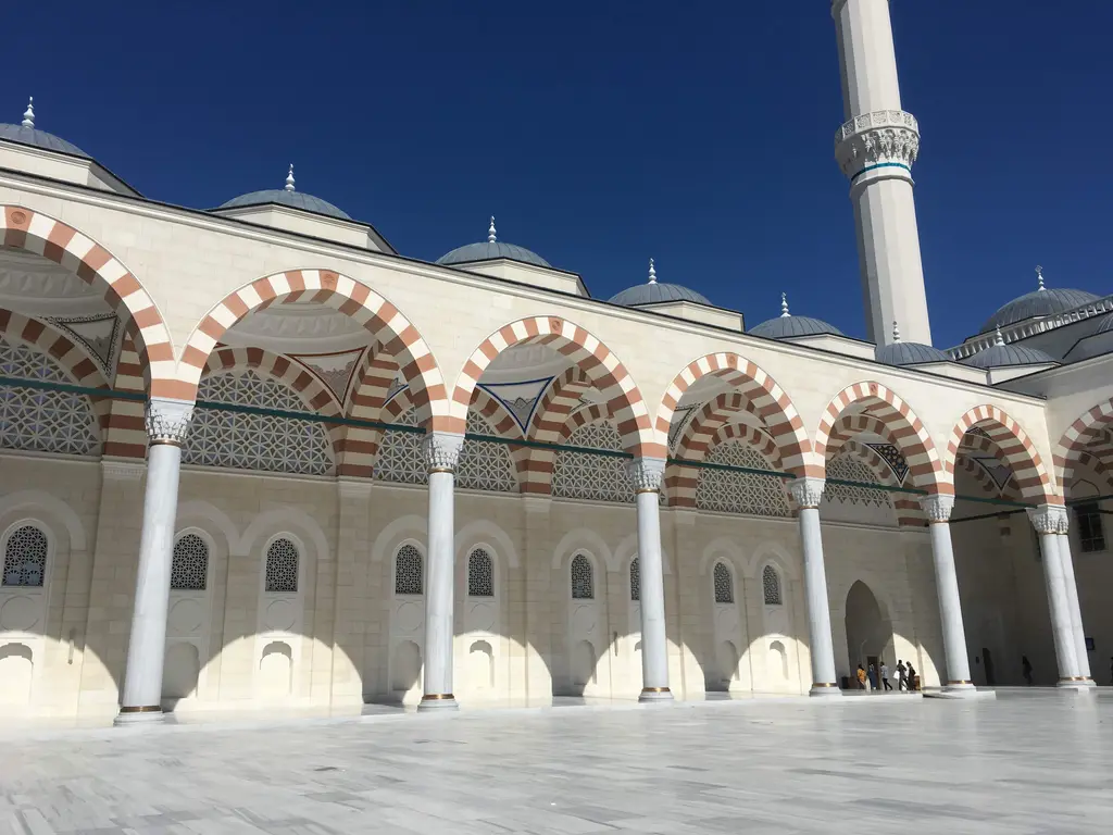Büyük Çamlıca Camii'nin avlusu; kırmızı beyaz kemerli revaklar, mermer sütunlar, kubbeler ve minare.