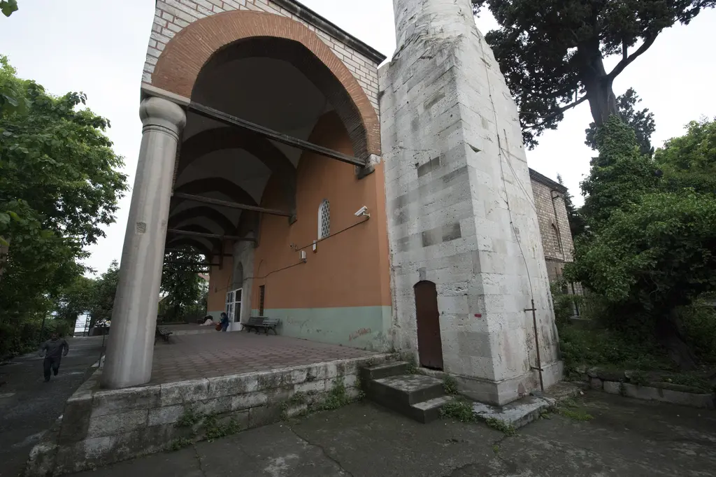 Rum Mehmed Paşa Camii'nin revak köşesi; tek sütuna oturan tuğla kemer, minare kaidesi ve arkada ağaçlar.
