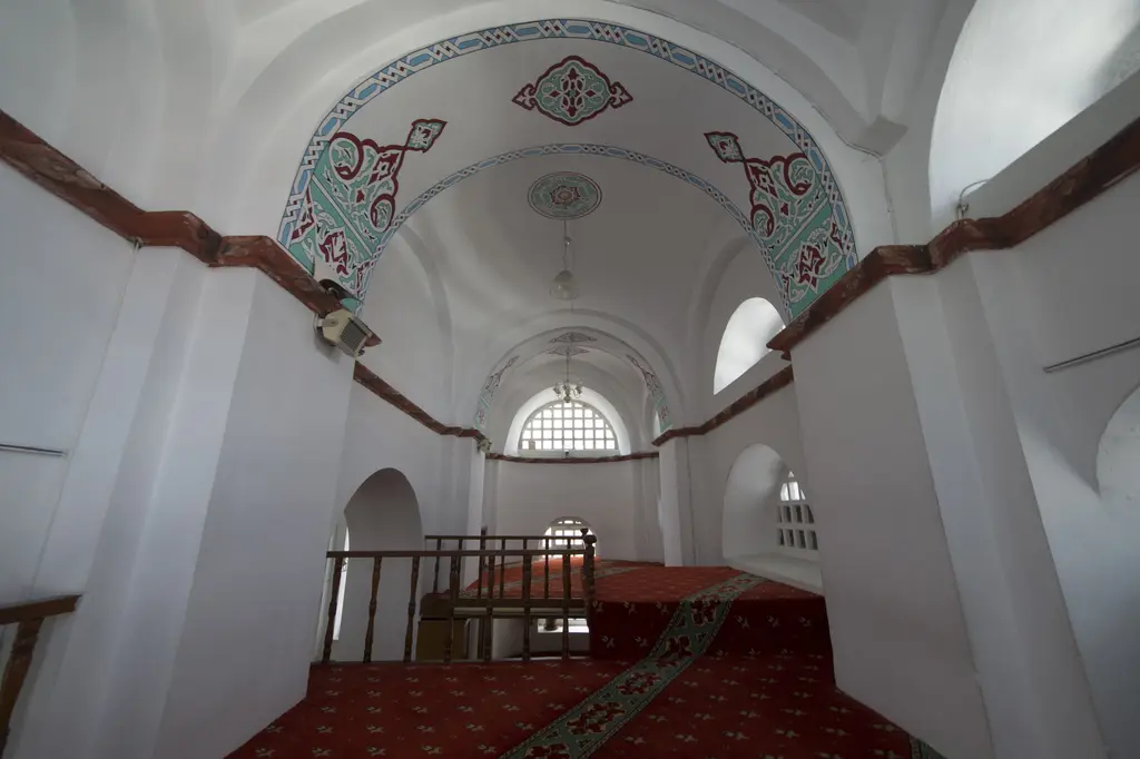 Bodrum Camii'nde üst kattaki kadınlar bölümü; beşik tonoz, yeşil ve bordo kalem işi bordür, kemerli kafes pencere, ahşap korkuluk ile merdiven başı.
