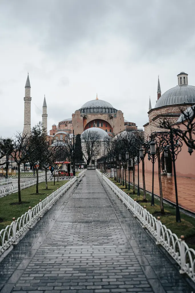 Sultanahmet'te sisli bir sabahta Ayasofya'ya inen taş yol; iki yanda lamba direkleri ile yapraksız ağaçlar, uçta kubbe ve minareler.