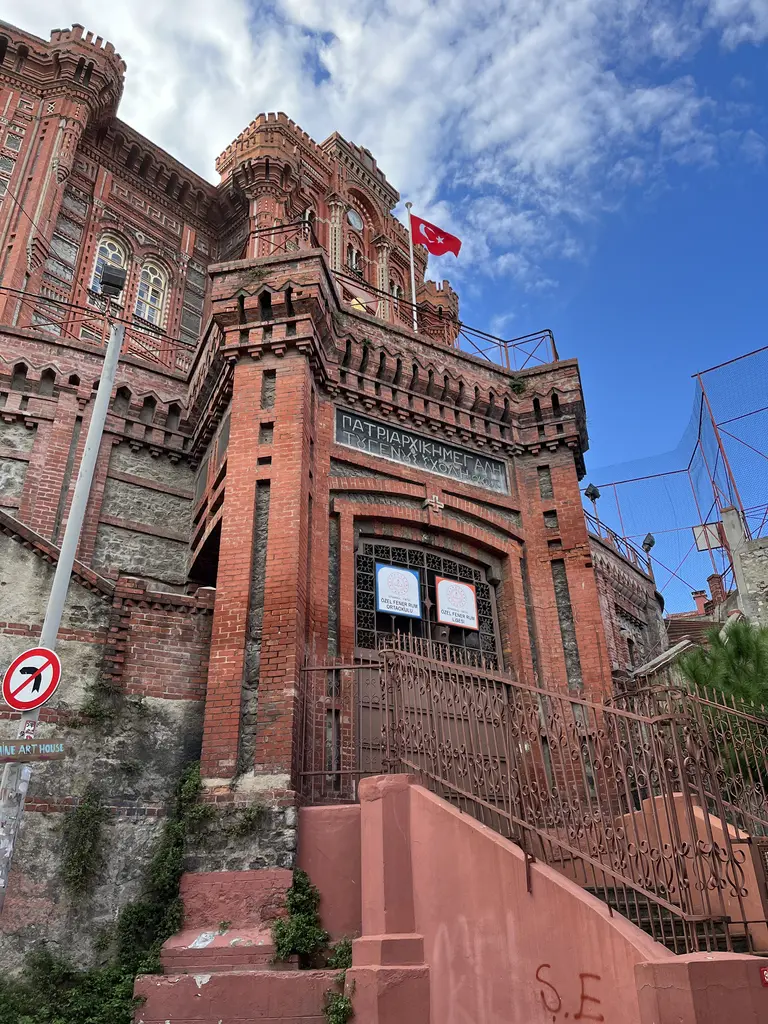 Bina dik açıyla aşağıdan; yüksek istinat duvarı, üstünde tuğla cephe ve en üstte kubbeli kule.