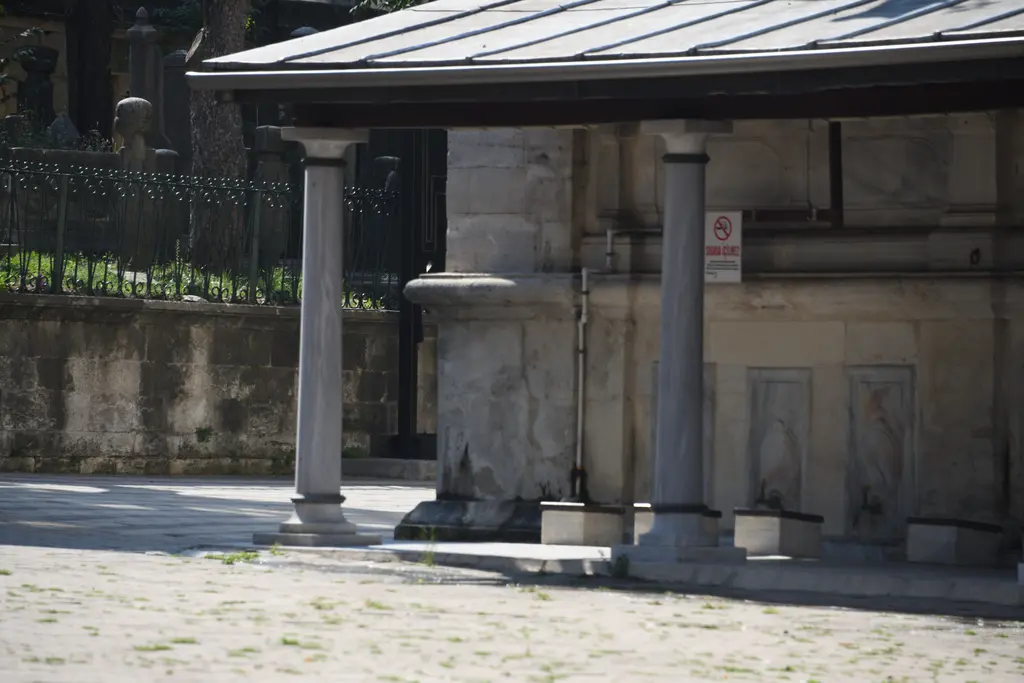 Selimiye Camii'nde abdest yeri; sütunlu saçağın altında taş duvara dizili musluklar ve önünde taş zemin.