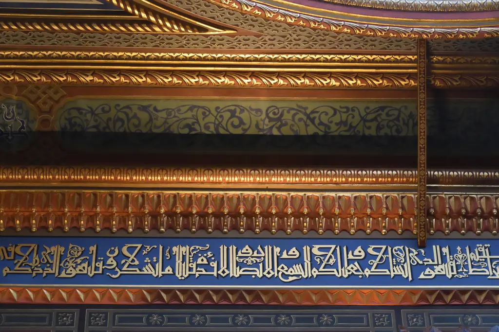 Yıldız Hamidiye Camii'nde yazı kuşağı; lacivert zemin üzerinde altın kufi harfler, üstte yaldızlı ve oymalı saçak.