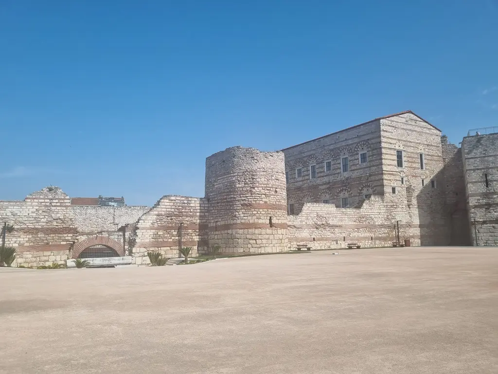 Tekfur Sarayı'nın geniş taş döşeli avlusu; boş meydanın karşısında saray gövdesi, iki yanda sur burçları ve açık gökyüzü.