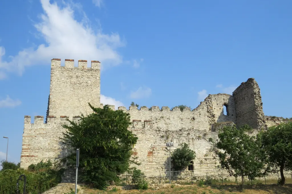 Yan yana iki kule; soldaki mazgallarına kadar onarılmış ve düzgün, sağdaki tepesi yıkık, gövdesi çatlamış ve otlarla kaplı.