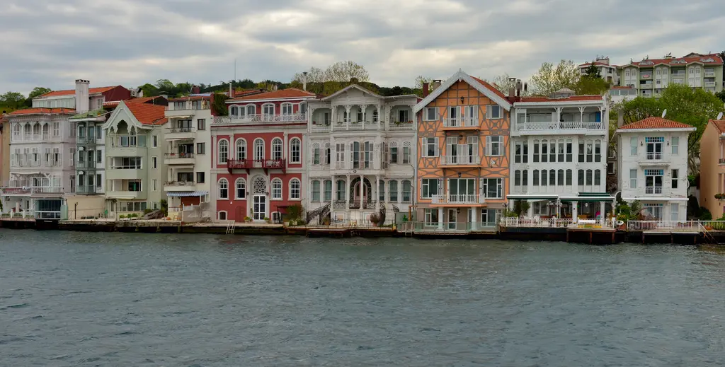 Boğaz'dan yalılar; kıyı boyunca beyaz, kırmızı ve turuncu ahşap ve taş yalılar, önde gri deniz.