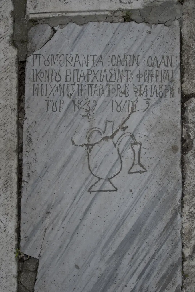 Mermer mezar taşı; üstte Yunan harfleriyle dört satır yazı, altında kazıma tekniğiyle işlenmiş bir testi ile kadeh kabartması.