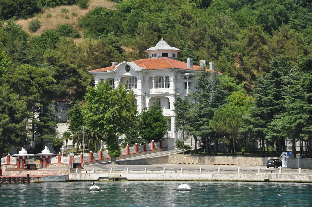 Anadolu Kavağı'nda Boğaz kıyısında beyaz Marko Paşa Köşkü; kiremit çatılı fenerli kule, ağaçlı bahçe ve önde rıhtım.