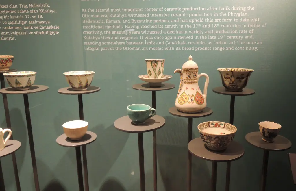 Pera Müzesi'nde ince ayaklı kaideler üzerinde duran çiçek desenli Kütahya kahve fincanları ve bir ibrik.