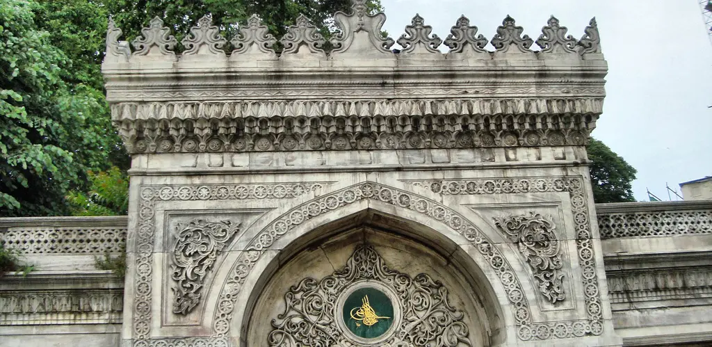 Pertevniyal Valide Sultan Camii'nin avlu kapısı; oyma taş kemer, ortada yeşil zeminli tuğra madalyonu ve mazgallı üst korniş.