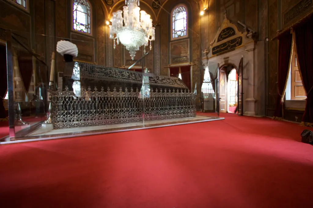 Fatih Sultan Mehmet Türbesi'nin içi; koyu kırmızı halı, ortada delik işli gümüş renkli şebekeyle çevrili sanduka, baş ucunda büyük beyaz kavuk ve üstte kristal avize.