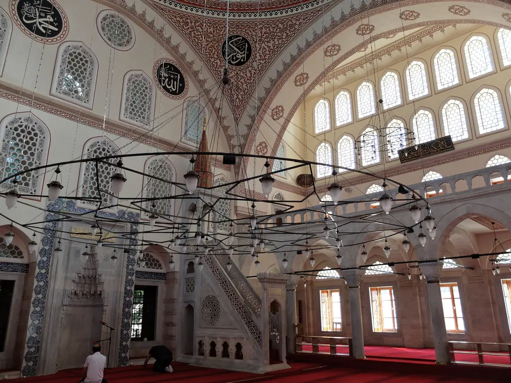 Zal Mahmud Paşa Camii'nin harimi; çini kaplı mihrap duvarı, mermer minber, sarkan avize çemberi ve pencereli kubbe kemerleri.