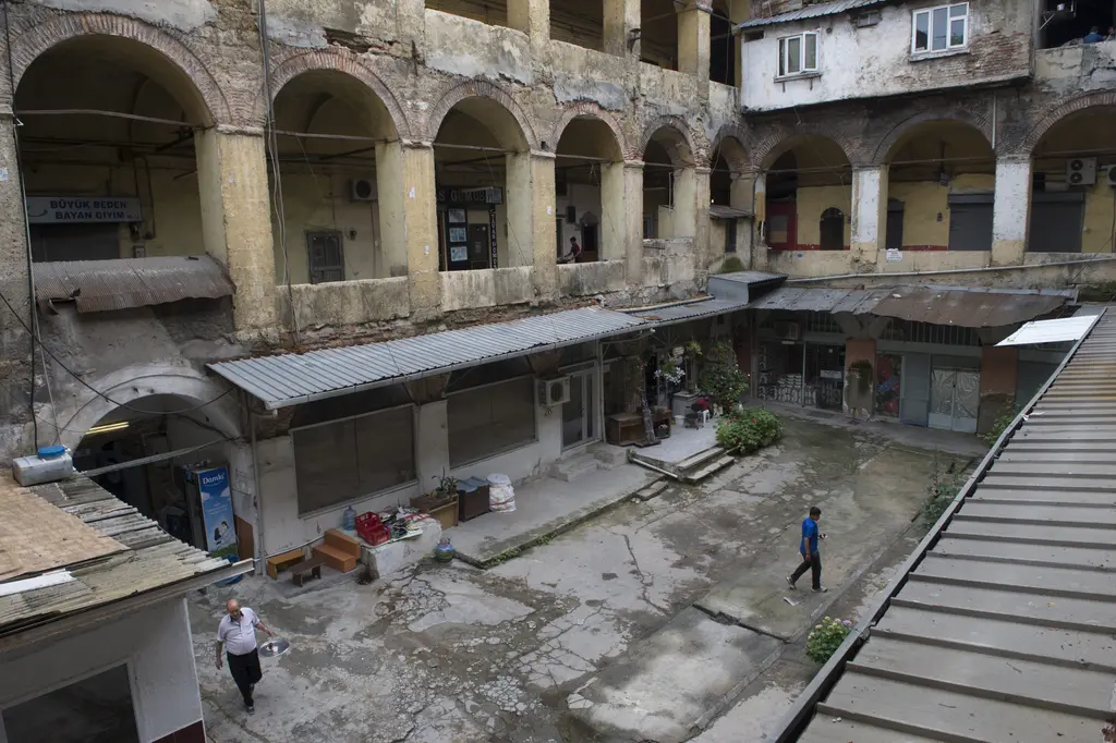Büyük Yeni Han'ın avlusuna üst kattan bakış; sundurmalı dükkânlar, yürüyen iki kişi ve arkada üst üste iki sıra kemer.