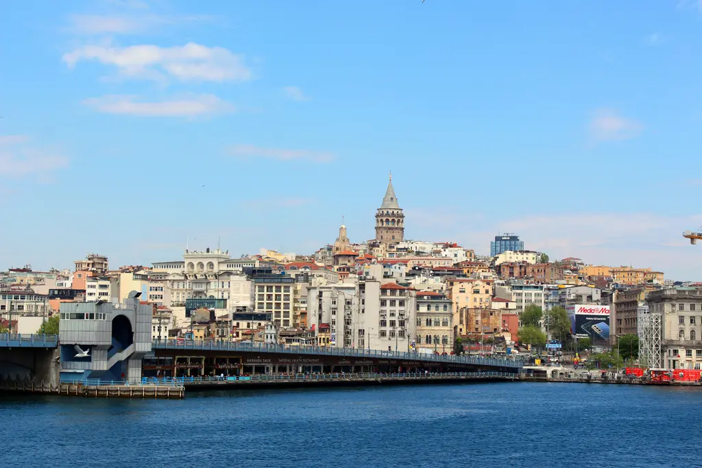 Haliç'ten Galata; önde Galata Köprüsü ve kıyıdaki iskele, arkada yamaca dizilen renkli binalar ve tepede kule.