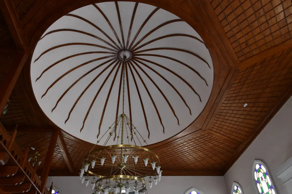 Şah Sultan Camii'nin tavanı; ahşap tavanın ortasında beyaz dilimli kubbe, kahverengi çıtalar ve kristal avize.