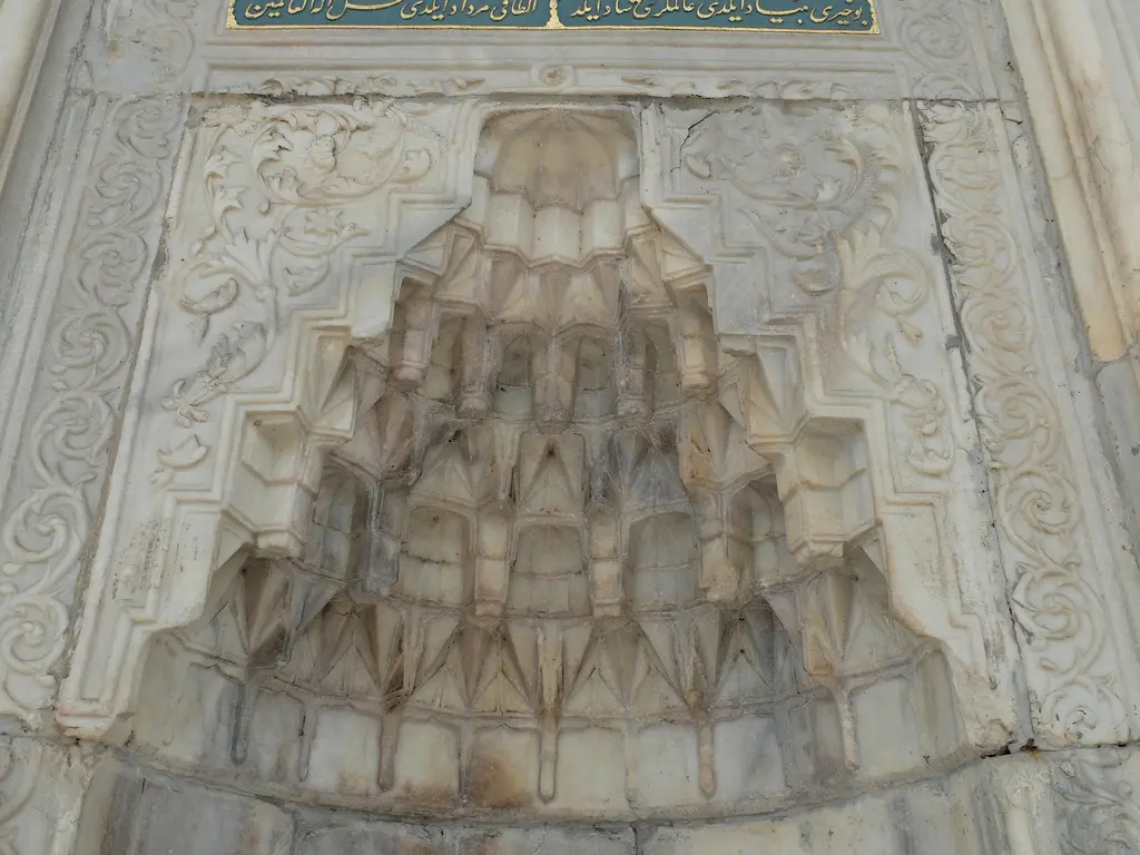 Tophane Çeşmesi'nde mukarnaslı niş; bal peteği gibi sıralanan prizmatik mermer dilimler ve çevresinde ince bitkisel kabartmalar.