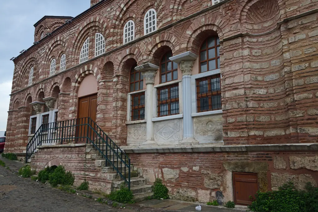 Vefa Kilise Camii'nin batı cephesi restorasyondan sonra; temiz tuğla ve taş bantlar, büyük boşaltma kemerleri, altta iki mermer sütunçeli revak gözü ve oyma korkuluk levhaları.