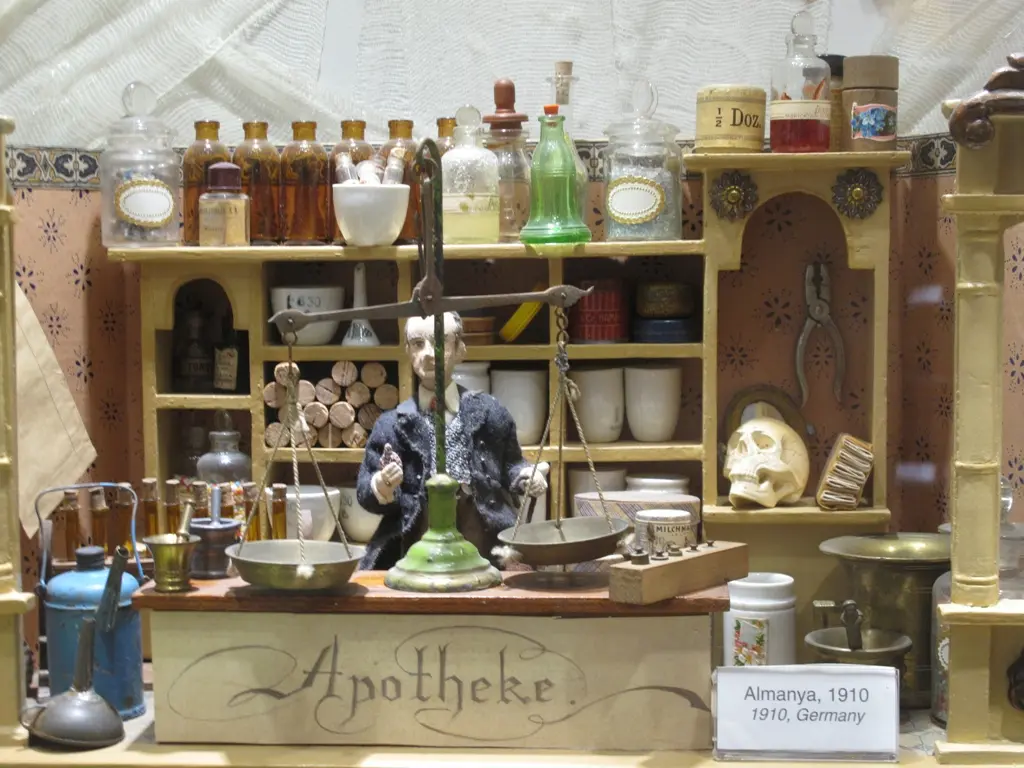 İstanbul Oyuncak Müzesi'nde oyuncak eczane; Apotheke yazılı tezgâh, raflarda minik şişeler, kavanozlar ve eczacı figürü.