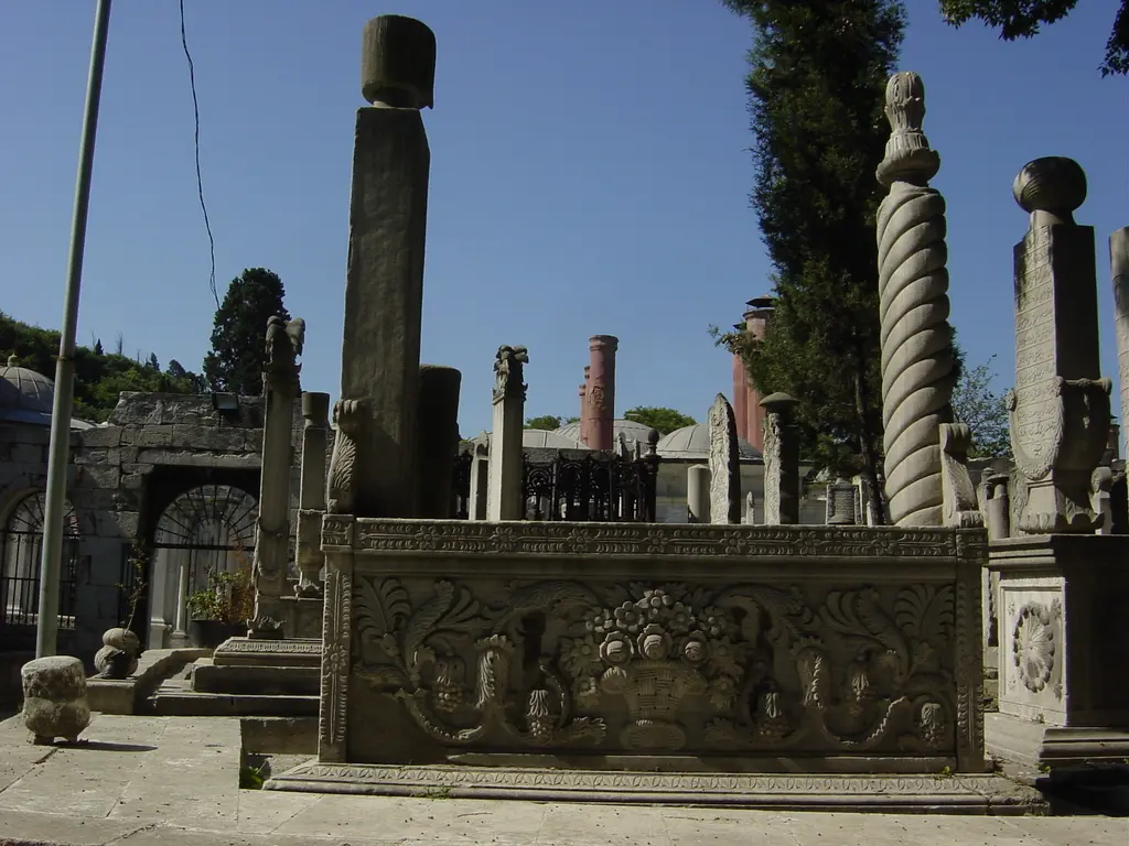 Eyüp Mezarlığı'nda oymalı lahit; kabartmalı taş sanduka, burmalı sütun biçimli taşlar ve arkada türbe kapısı.