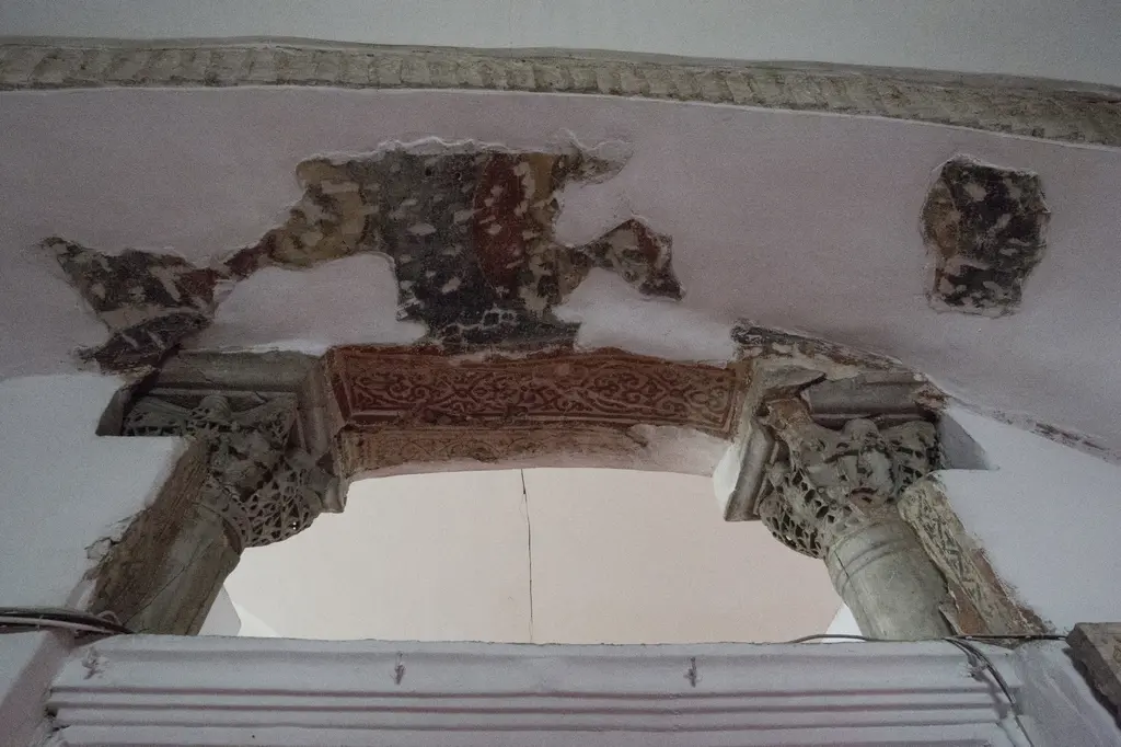 Kalenderhane Camii'nde narteks kapısının üstü; iki oymalı sütun başlığı, kırmızı zeminli sarmal bitki bandı ve sıvanın altından görünen eski boya parçaları.