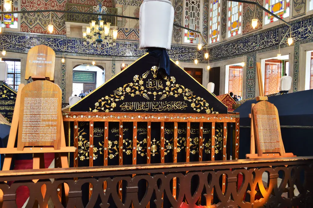 I. Ahmed'in sandukası; sedef kakmalı ahşap parmaklık içinde altın yazılı siyah örtü, başında sarık, iki yanında tanıtım levhaları.