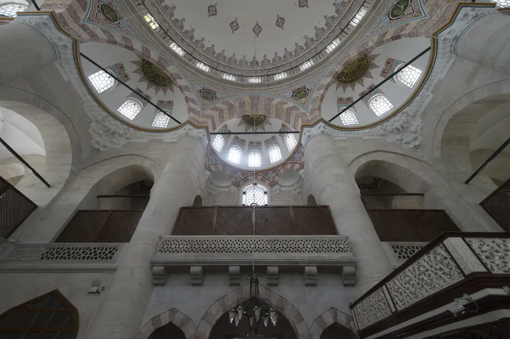 Nişancı Mehmed Paşa Camii'nde galerilerden yukarı bakış; kalın ayaklar, yarım kubbeler, sivri kemerli pencereler ve mermer şebekeli korkuluklar.