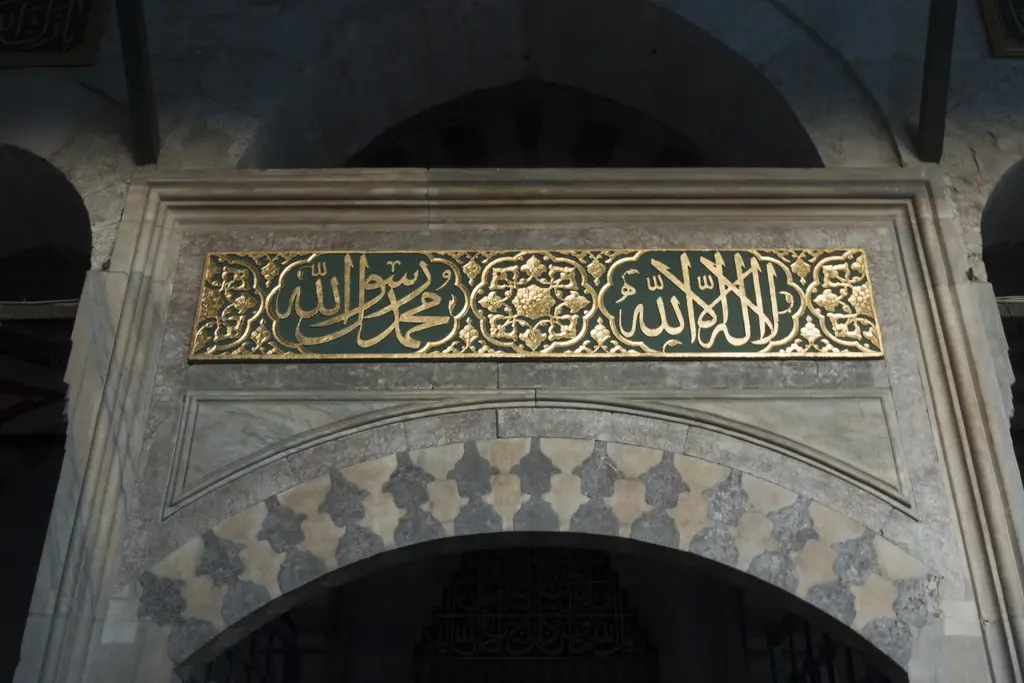Kılıç Ali Paşa Camii'nin harim kapısı; mermer çerçeve, altın yaldızlı yazı kuşağı ve kemerin üstünde mukarnaslı taş süsleme.