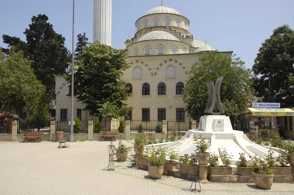 Şile merkezinde meydan; kubbeli büyük bir cami, önünde beyaz anıtlı çeşme havuzu, saksılar ve ağaçlar.